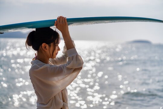 Group of surfers at sunset preparing for evening ride on ocean waves at beach