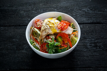 bibimbap with mushroom sprouts and chicken in a plate on a black background
