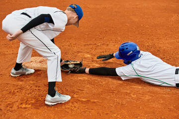 Two teenage boys compete energetically in a thrilling baseball game on the field