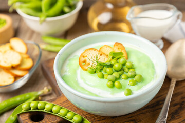Green pea soup on a wooden table. Fresh pea soup bowl. Delicious healthy cream soup in a bowl with green peas and croutons. Healthy vegan puree. Copy space. Space for text.