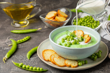 Green pea soup on a wooden table. Fresh pea soup bowl. Delicious healthy cream soup in a bowl with green peas and croutons. Healthy vegan puree. Copy space. Space for text.
