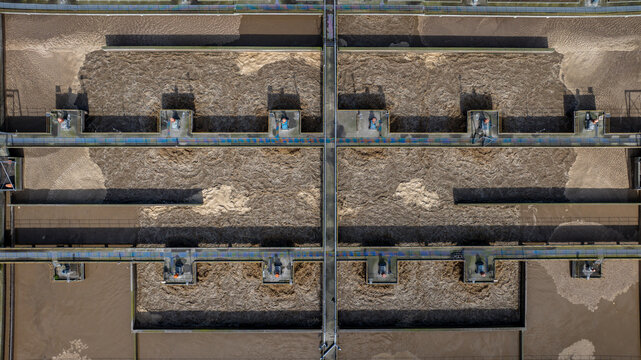 Wide overhead view of agitator or aerator ponds at a waste water treatment facility. Brown waste water in process of being cleaned from sediment. 
