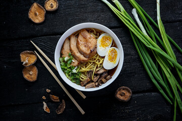 Phobo soup in a white plate with egg and greens on a dark background with decor
