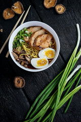 Phobo soup in a white plate with egg and greens on a dark background