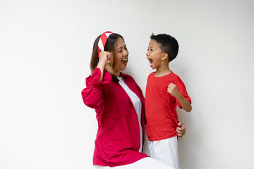 A happy Indonesian mother and child celebrating Independence Day together with joyful expressions. Dressed in red and white outfits, they show pride and unity while holding flags and smiling.