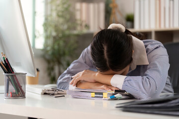Office Syndrome: Exhausted young woman resting her head on paperwork at desk