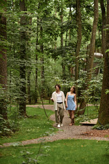 Fototapeta premium Young couple enjoys a romantic stroll through a serene park on a beautiful day