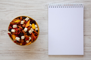 Healthy Dried Fruit and Nut Mix in a Bowl, blank notepad, top view.