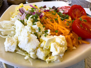 Fresh vegetable salad with feta cheese, grated carrots, red onions, and cherry tomatoes