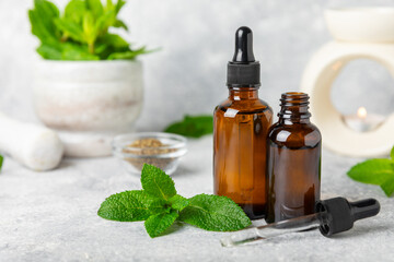 Essential oil mint on a wooden background. Peppermint essential oil with fresh mint leaves. A bottle of aromatherapy oil. Mint extract. The concept of natural cosmetics, spa care. copy space