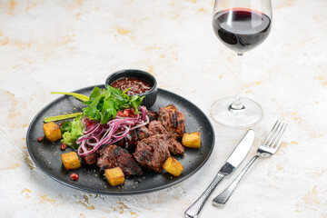 fried kebab on a plate with green onions and sauce on a background with wine