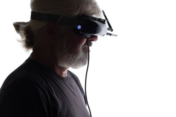 silhouette of bearded elderly man operating FPV drone in googles on his head, studio shot of man and modern technologies