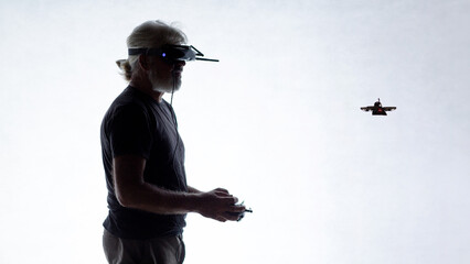 Bearded senior pilot with FPV goggles and drone controller on white isolated background, modern male hobby and technology