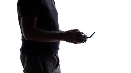 man holding in hands remote control of flying quadcopter, silhouette studio shot of modern human hobby and technology