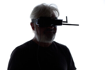 silhouette of bearded elderly man operating FPV drone in googles on his head, studio shot of man and modern technologies