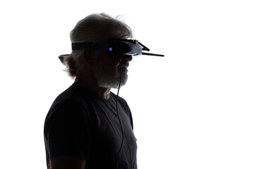 silhouette of bearded elderly man operating FPV drone in googles on his head, studio shot of man and modern technologies