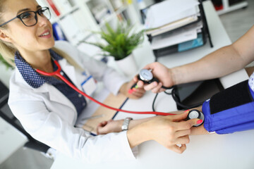 Health check-up with a medical professional examining a patient's blood pressure in a bright clinic setting
