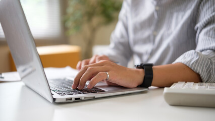 Close up of online seller typing on laptop while managing e-commerce business at home. E-commerce concept.