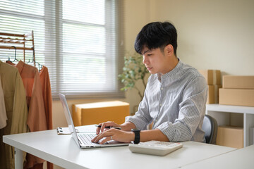 Small business owner working on laptop for online store management in a home office. E-commerce concept.