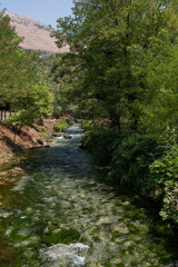 A wide horizontal view of the Blue Eye (Syri i Kaltër) spring in southern Albania, showcasing turquoise water, lush greenery, and a peaceful natural setting.