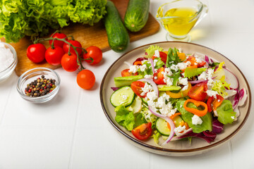 Cucumber salad on a wooden background.Homemade salad with fresh vegetables, cucumber, tomato, sweet pepper and lettuce in a plate.Vegetarian spring salad.Vegetarian diet.Healthy eating.Space for text