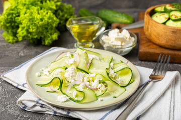 Cucumber salad on a wooden background.Homemade salad with fresh vegetables, cucumber, tomato, sweet pepper and lettuce in a plate.Vegetarian spring salad.Vegetarian diet.Healthy eating.Space for text