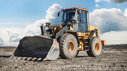 Heavy machinery works on construction site under clear blue sky with clouds