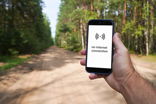 Hand holding a smartphone with no internet connection in a forest road