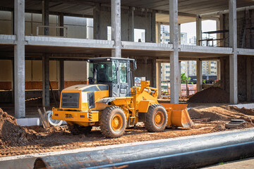 Construction site with yellow loader machinery working on new building project during daytime