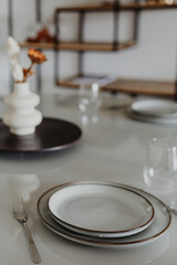Elegant table setting with ceramic plates, wine glasses and minimal decor