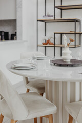 Elegant dining setup with white table and white chairs in modern bright living room