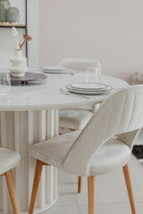 Elegant dining setup with white table and white chairs in modern bright living room