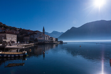 Fototapeta premium Distant view of the historic town of Perast, Montenegro, on a peaceful winter evening. The Adriatic coast with soft fading light creates a serene Mediterranean atmosphere.