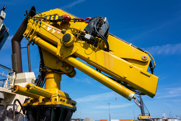 Close-Up of Heavy-Duty Yellow Hydraulic Crane Arm on Industrial Ship Deck. Modern Marine Construction Equipment for Lifting, Engineering, and Offshore Operations © dechevm