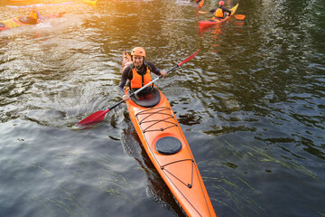 Happy kayaker guy floating on the surface of water in river during kayaking skill training