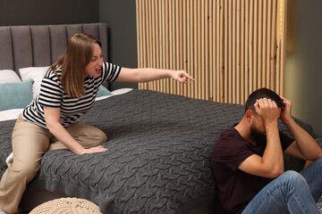 Betrayal. Angry woman shouting at her husband on bed at home