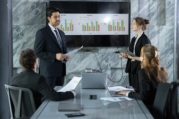 Business professionals in modern conference room presenting data charts during a meeting, discussing strategies and analyzing performance for corporate growth and success.