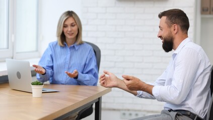 Obraz premium Smiling business partners working with laptop at table in office