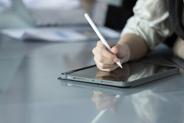 Close-up of hand of businessperson using pen take note on digital stylus on tablet in modern office, illustrating technology, creativity, and digital workflow in professional business.
