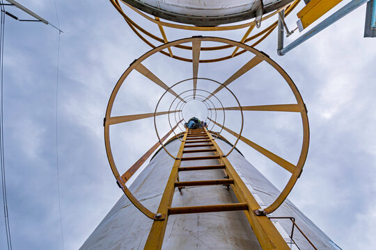 Male worker climbs up the ladder inspection stainless tank work at height