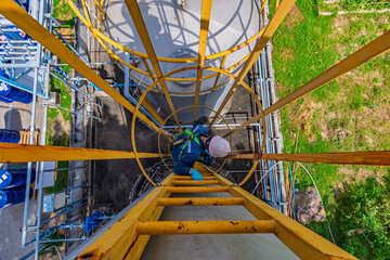 Male worker climbs up the ladder inspection stainless tank work at height