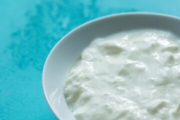 natural yoghurt in white bowl on blue background