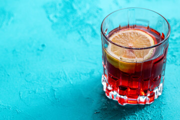 Lemon slices in red cocktail in crystal glass on blue background