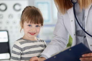Smiling child during a checkup in a bright clinic with a caring doctor wearing a white coat in a friendly atmosphere