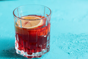 Lemon slices in red cocktail in crystal glass on blue background