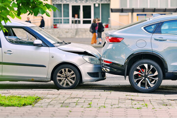 Rear end collision between two cars on urban street with visible damage to bumper and hood, traffic accident. Damaged vehicles after rear end crash on city road, clear impact and crumpled front bumper © Tricky Shark