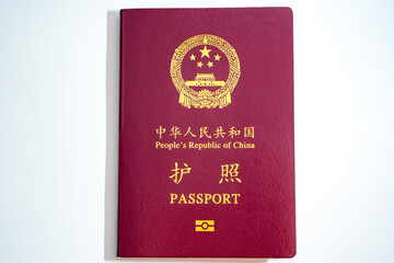 A close-up view of the cover of a dark red passport from the People's Republic of China, featuring the national emblem and 