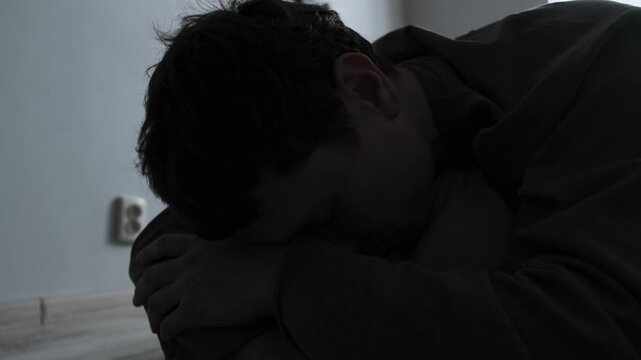 Sadness and pain after breakup. Close-up of young man lying on bed looking at old photos from when he was with his ex girlfriend.