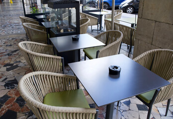 Outdoor cafe seating with stylish wicker chairs and modern tables in a vibrant urban setting with copy space