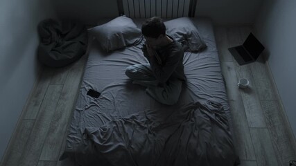 Sadness and pain after breakup. Young man sitting on bed holding photo of ex girlfriend, hugging it tightly, feeling deep pain and loneliness.